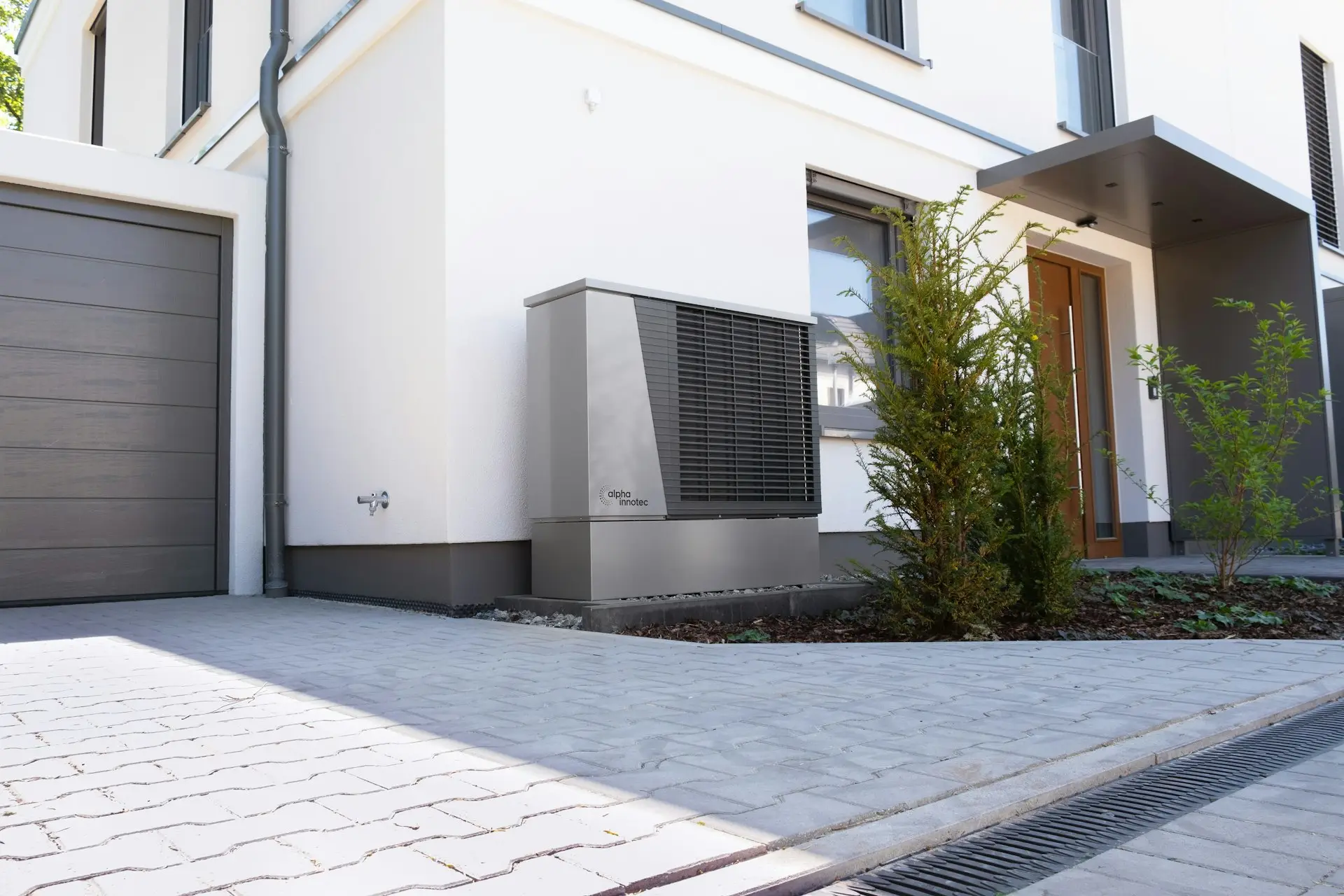 Unité extérieure de pompe à chaleur grise devant une maison moderne